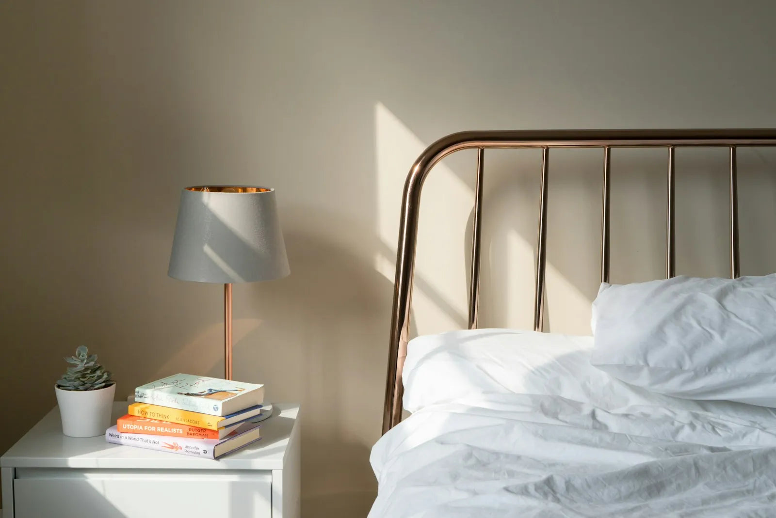 Bright bedroom with a made bed, white bedding and a bedside lamp